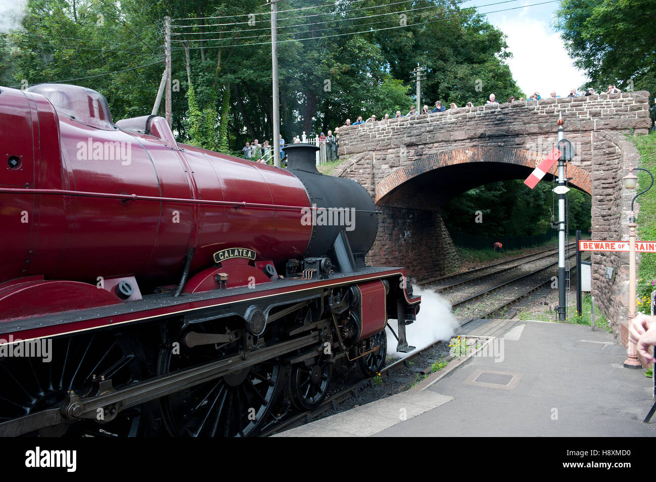 A steam locomotive waits at the lower quadrant semaphore starting signal at  on the West somerset Railway, UK Stock Photo