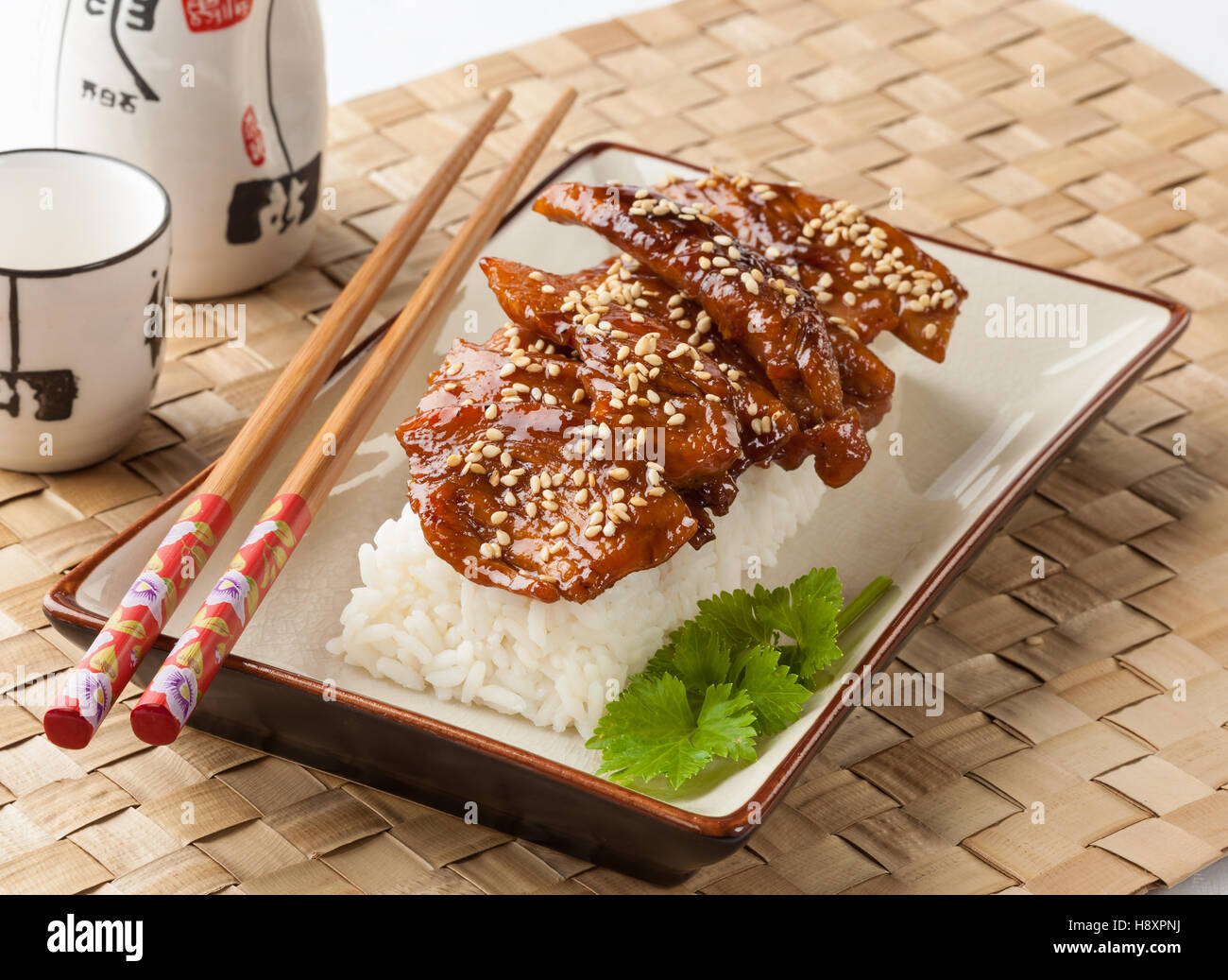 Teriyaki chicken served with rice on a rectangular plate. Stock Photo