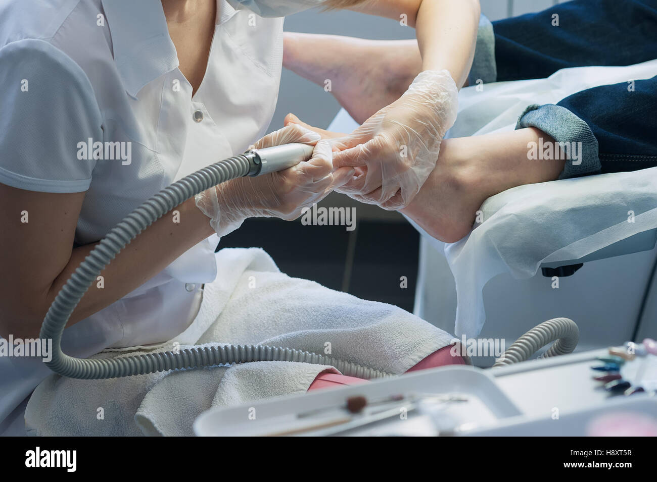 profesional nail technician sanding nails with machine Stock Photo