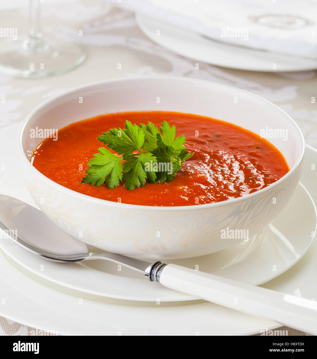 Fresh homemade tomato soup in a white bowl, garnished with parsley. Stock Photo