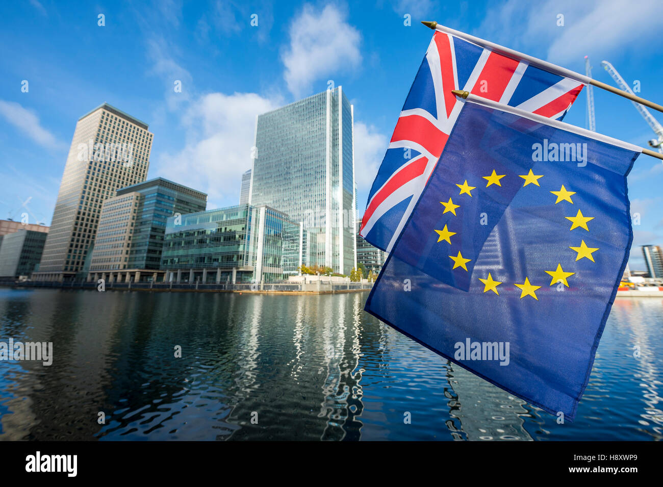 European Union and Union Jack flags flying above modern business towers of the financial center of Canary Wharf in London UK Stock Photo