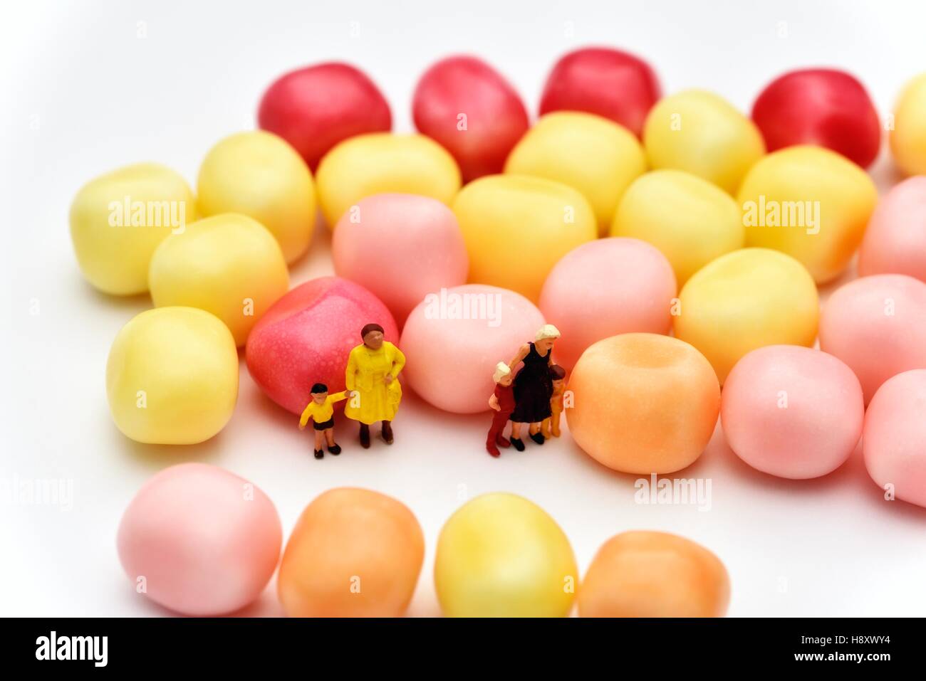 Miniature figurine mothers and children standing next to candy sweets Stock Photo