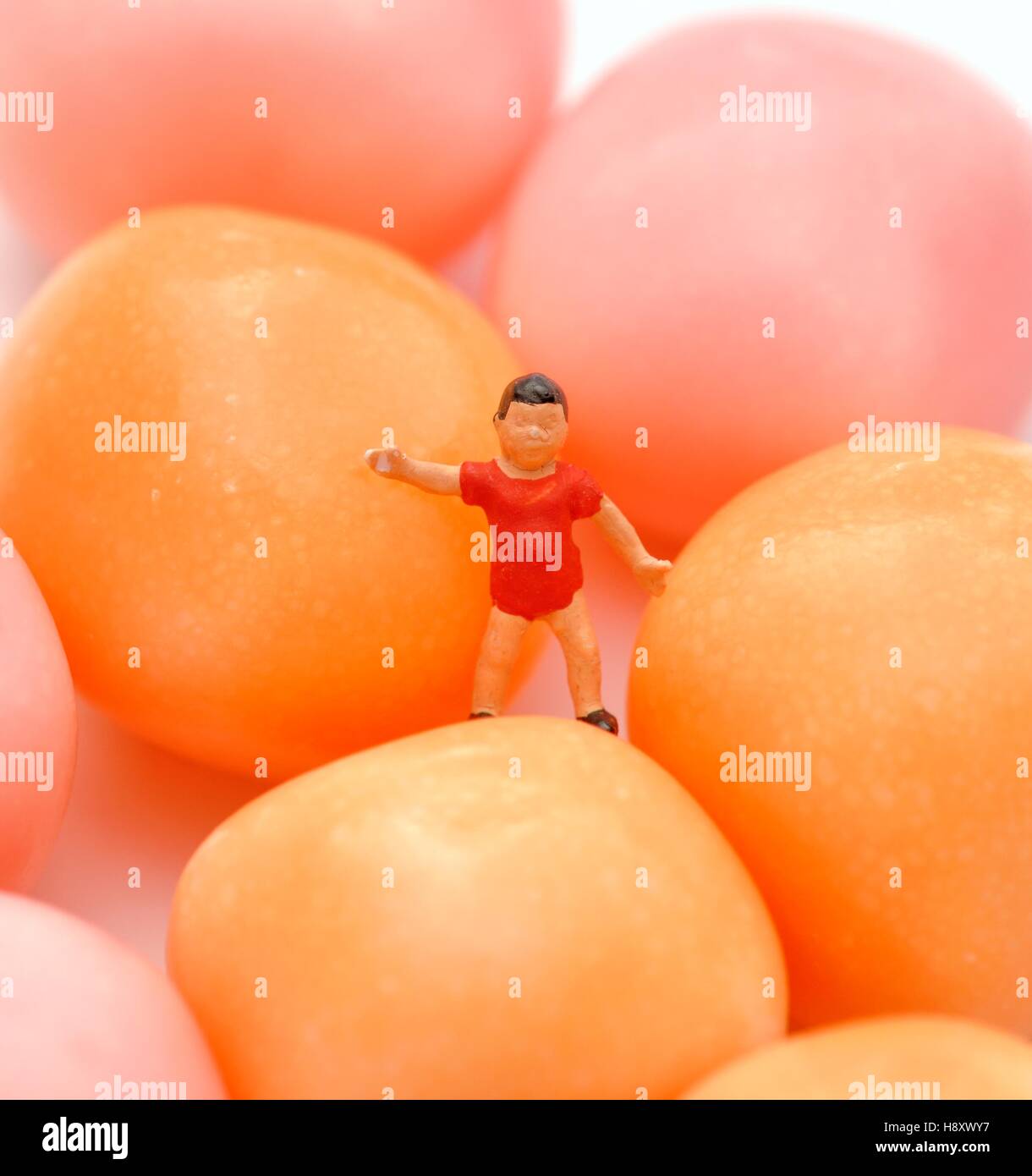 Miniature figurine young boy standing next to candy sweets Stock Photo