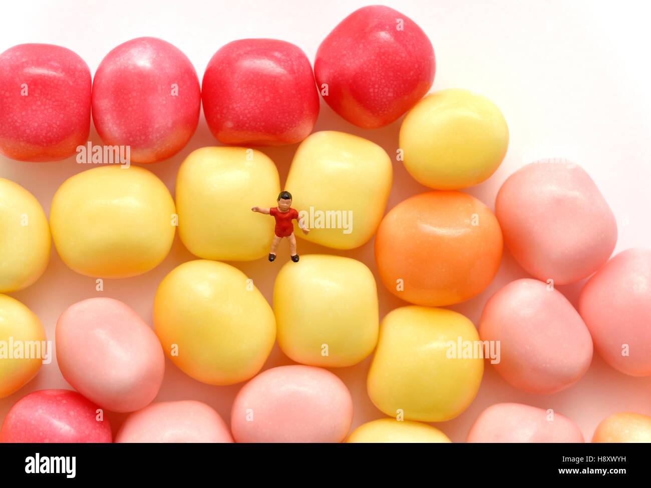 Miniature figurine young boy standing on some candy sweets Stock Photo