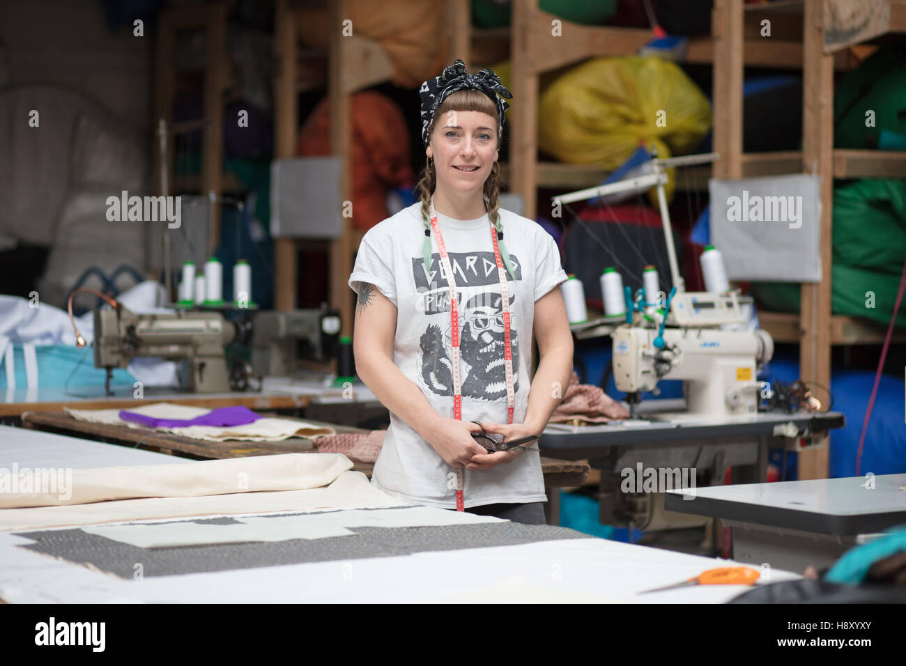 Portrait of a young tattooed seamstress in a factory environment Stock Photo