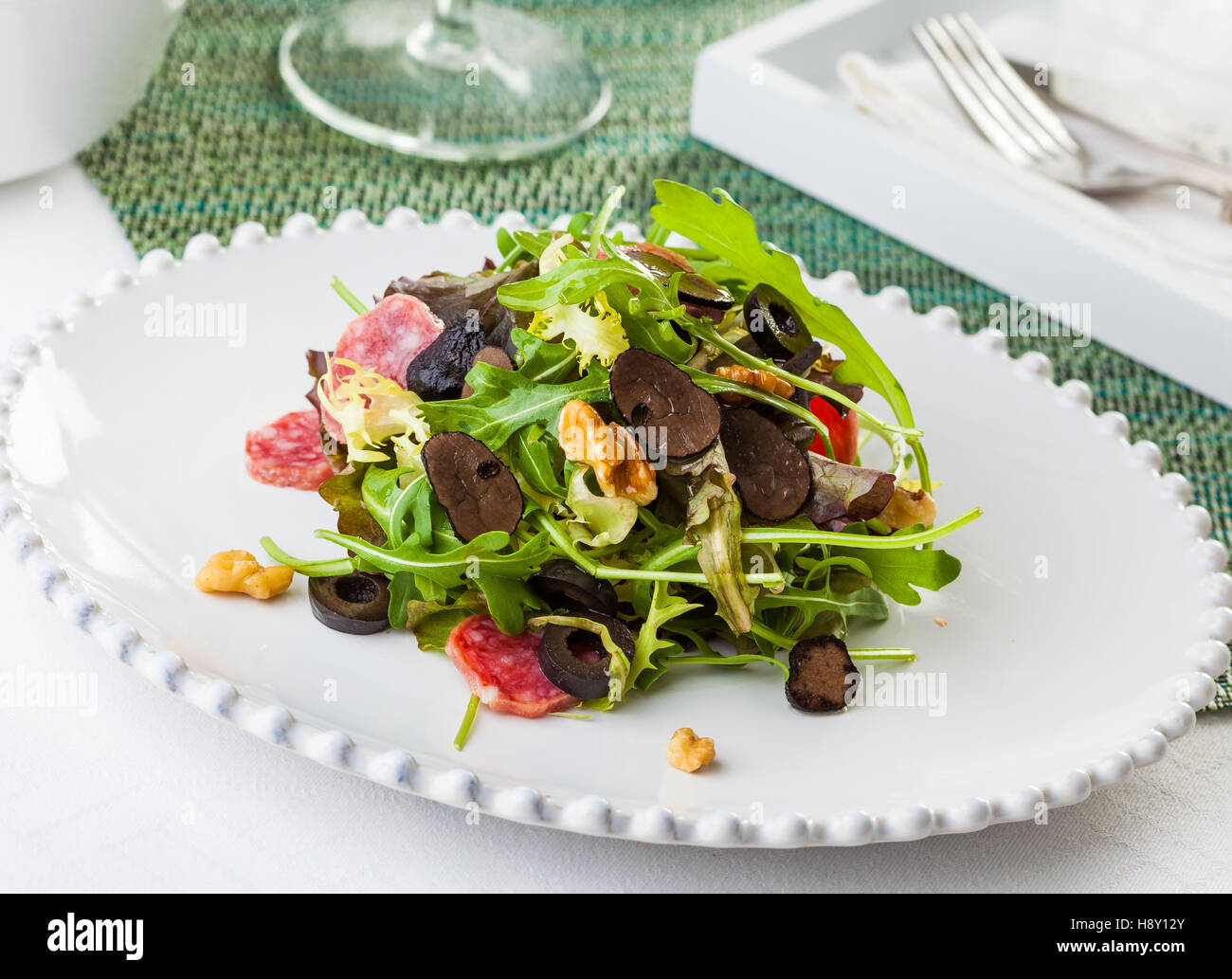 A delicious salad with arugola, black truffle, black olives, salami, walnuts Stock Photo
