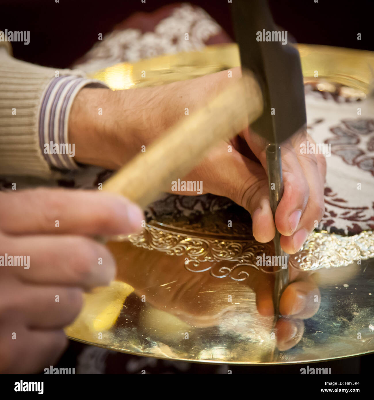 Abdelgabar Guernani engraves an ornament into a brass plate with a hammer and chisel in his workshop in the Talâa Seghira, Fès, Morocco. Stock Photo