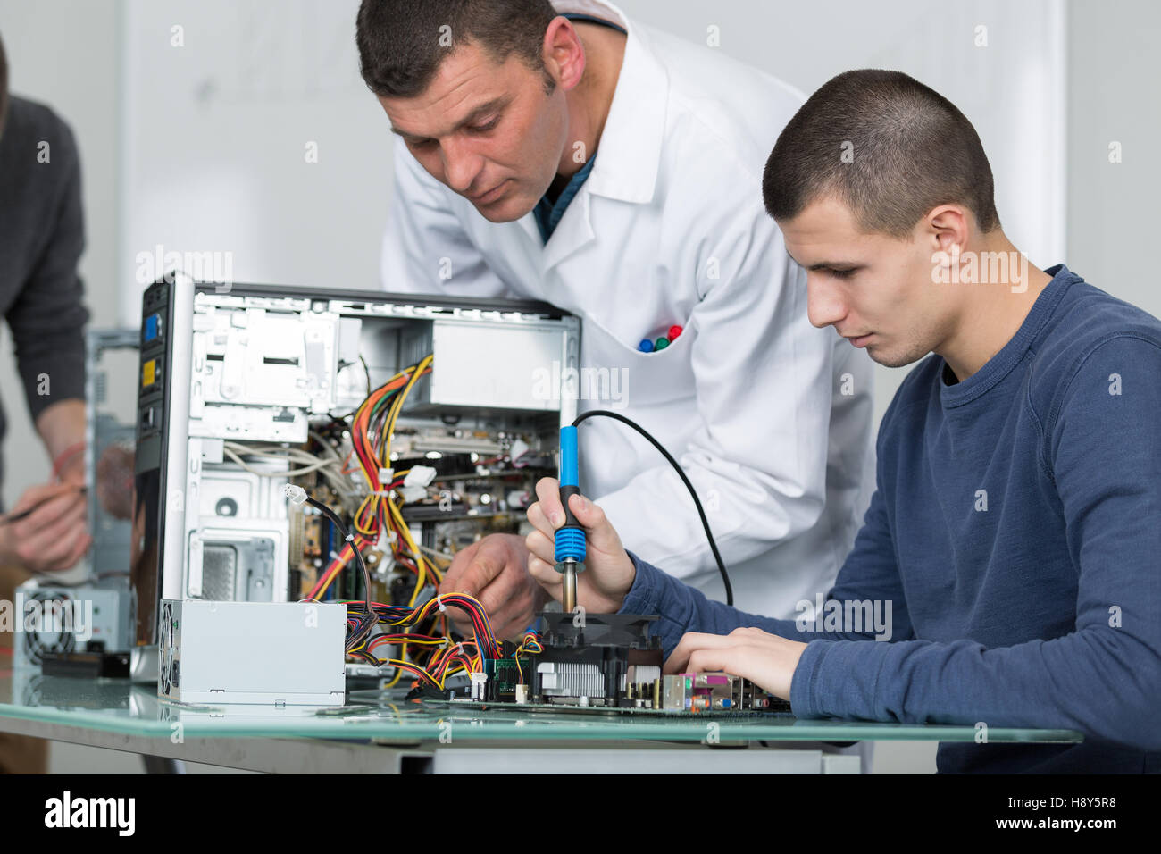male teacher assisting a young man in fixing computer Stock Photo - Alamy