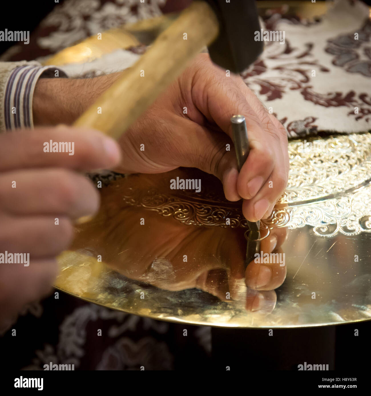 Hammer and chisel strike precisely on a brass plate, worked by brass craftsman Abdelgabar Guernani in his workshop in Fès, Morocco. Stock Photo
