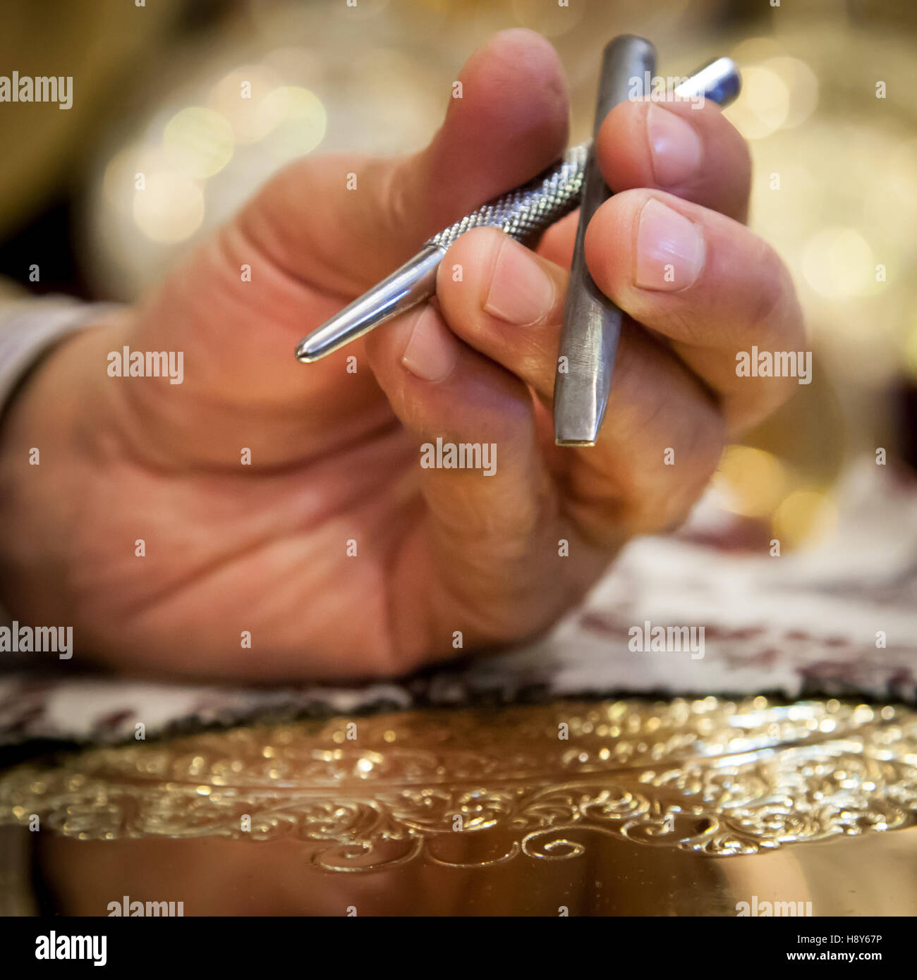 Two fine chisels rest in the hand of brass craftsman Abdelgabar Guernani. He uses them to engrave ornaments into brass plates in his workshop in Fès, Morocco. Stock Photo
