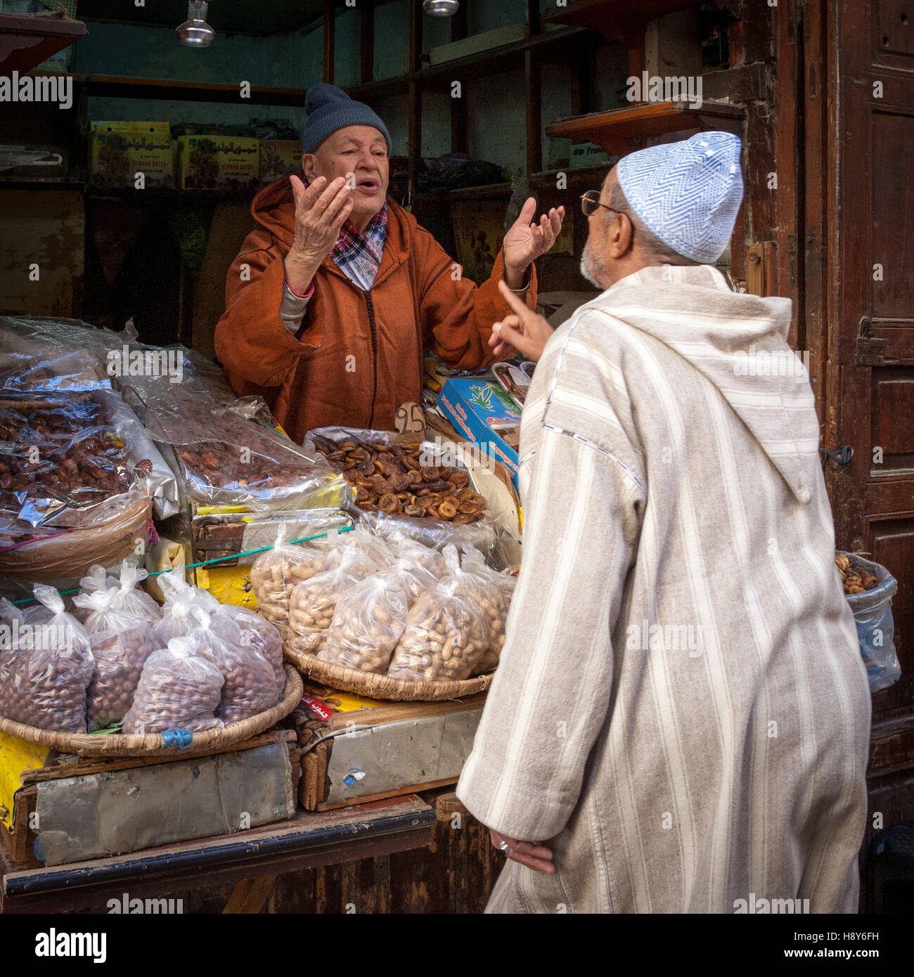 Two men negotiating about nuts and figs in Fès. In Morocco you can also talk about prices at every retailer. Traditionally, however, bargaining means more to people than just reducing the price Stock Photo