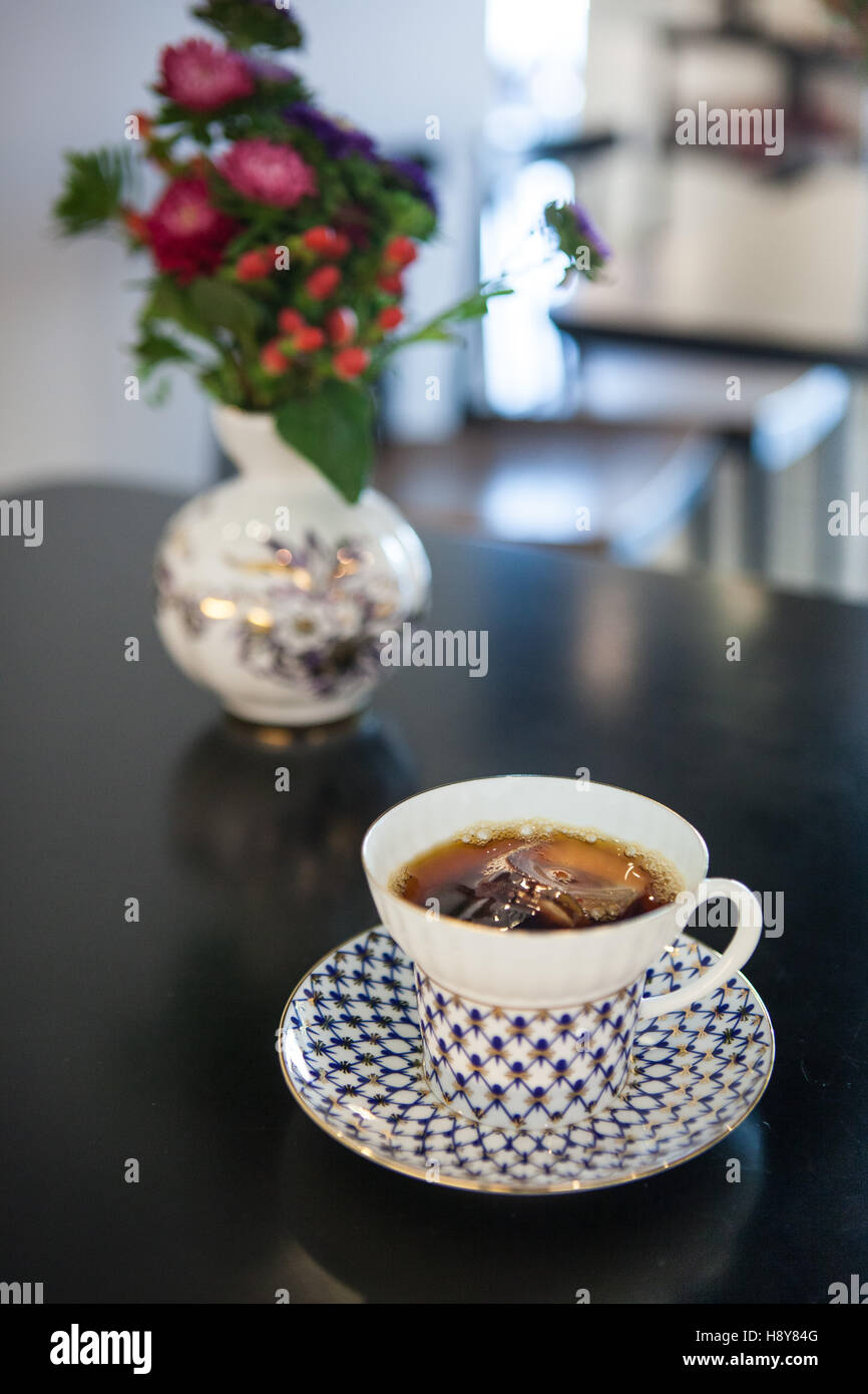 a cup of coffee with ice on the flowery table. Stock Photo