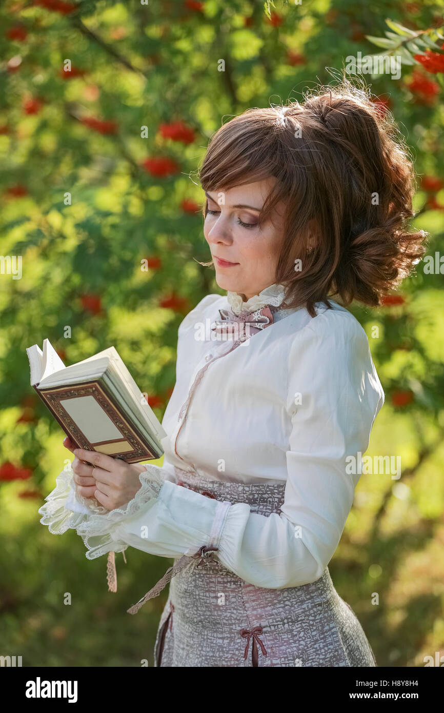 Woman Reader Young woman reading a book on the nature surrounded by mountain ash ...