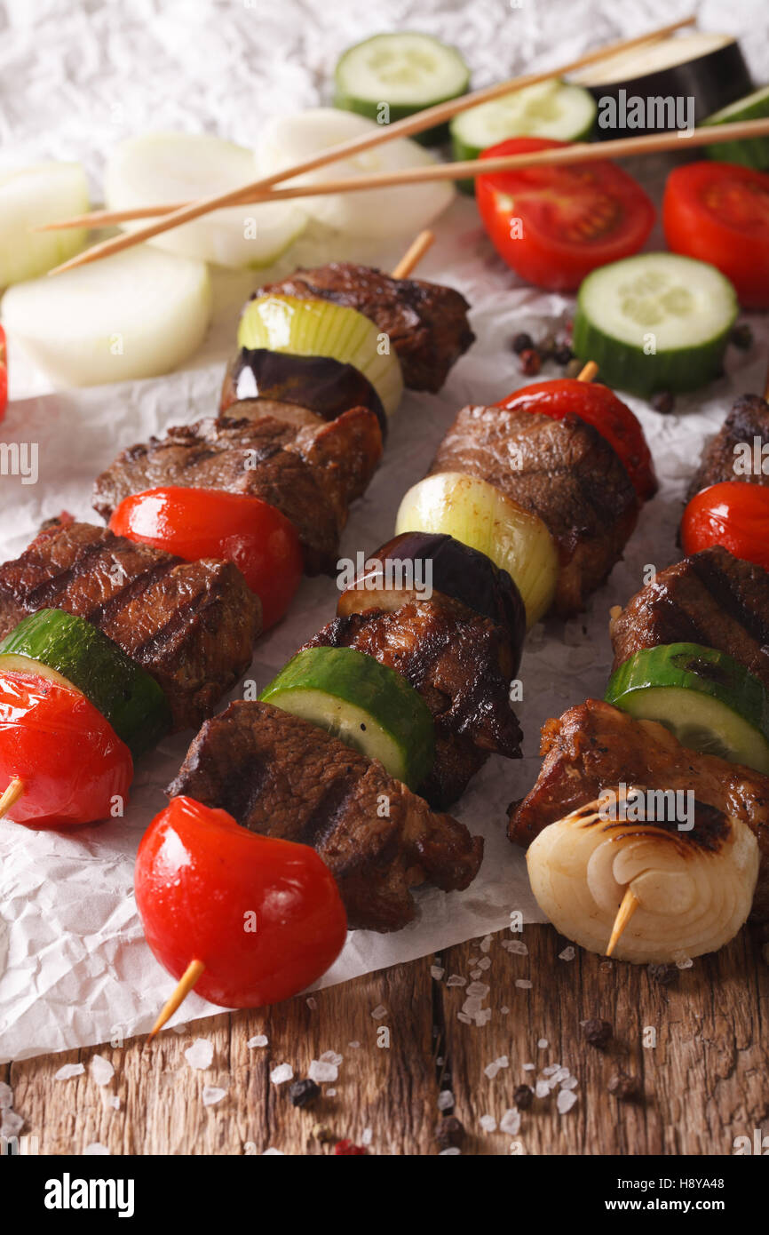 Tasty kebab with vegetables on skewers close-up on the table. Vertical Stock Photo