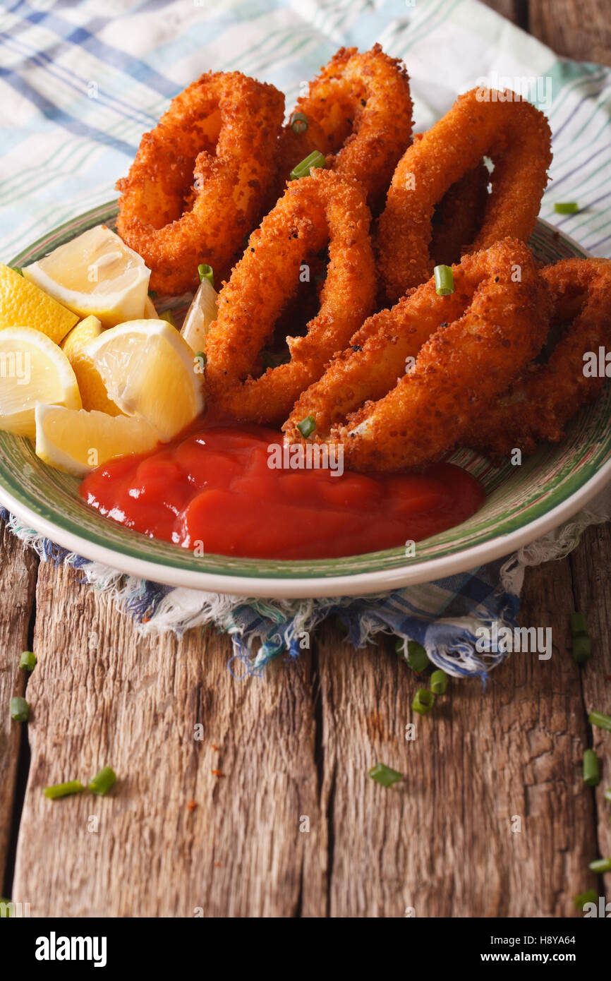 fried calamari rings close up with ketchup and lemon on a plate. vertical Stock Photo