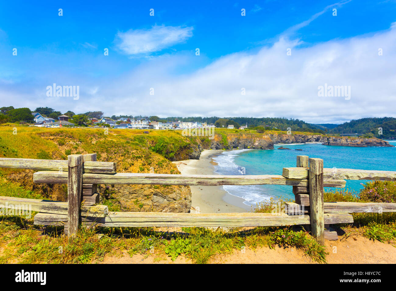 View through rustic wooden fence of sand beach below Main Street and houses of Mendocino town communinty on a sunny summer day Stock Photo