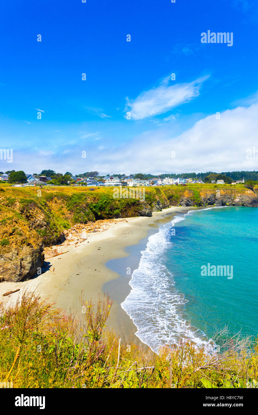 View of sand beach below Main Street and houses of Mendocino town communinty on a sunny summer day in California. Vertical Stock Photo