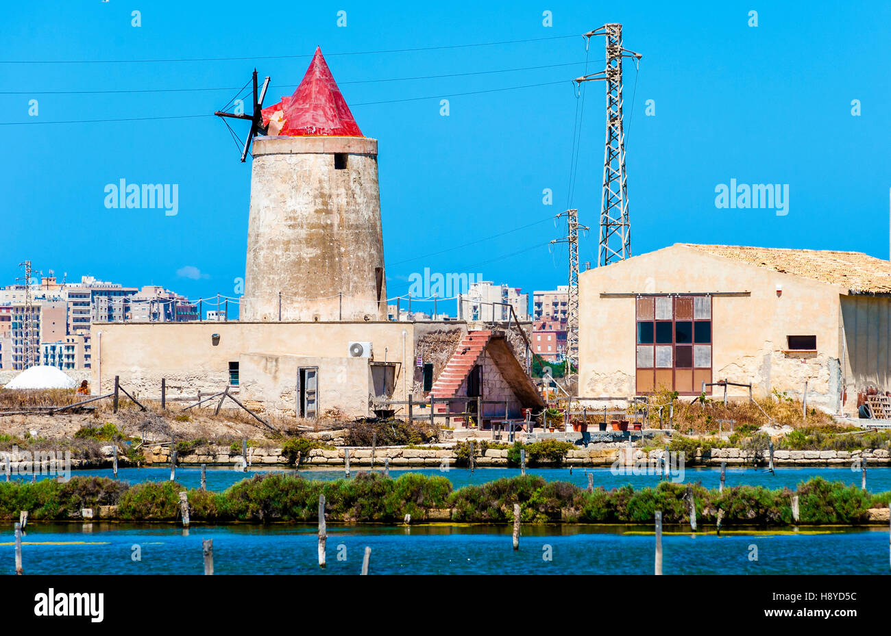 abandoned windmill in a plant for the production of sea salt (salina). Trapani, Sicily. Italy Stock Photo