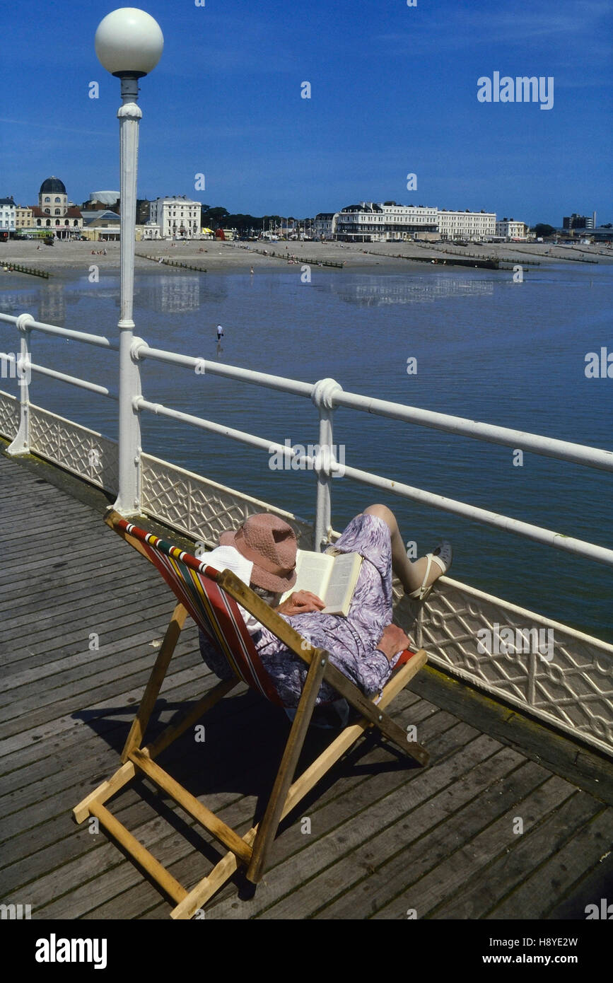 A mature woman reading in a deckchair on Worthing pier. West Sussex. England. UK Stock Photo