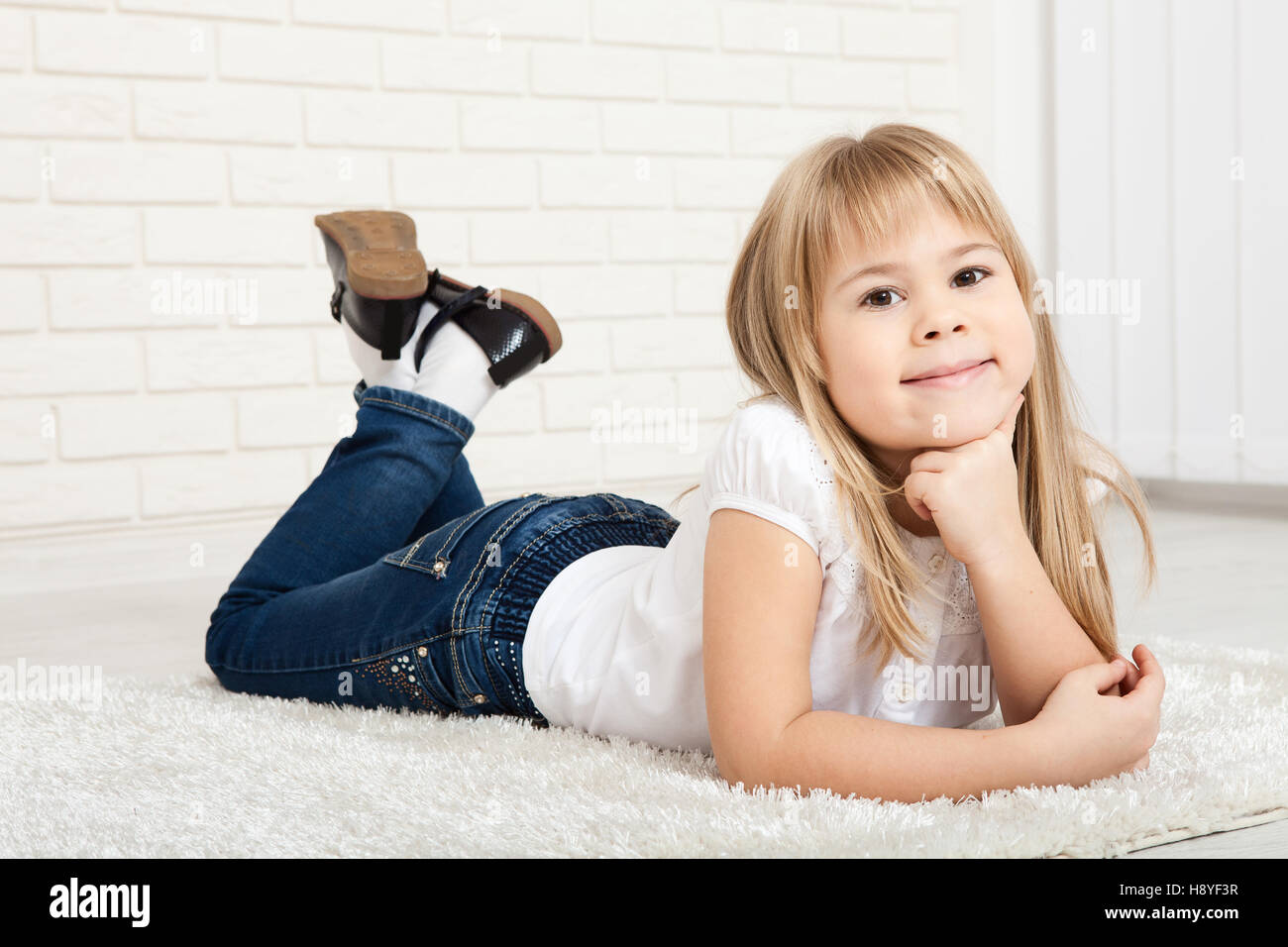 Smiling child girl in cloths lying on floor and relaxing Stock Photo
