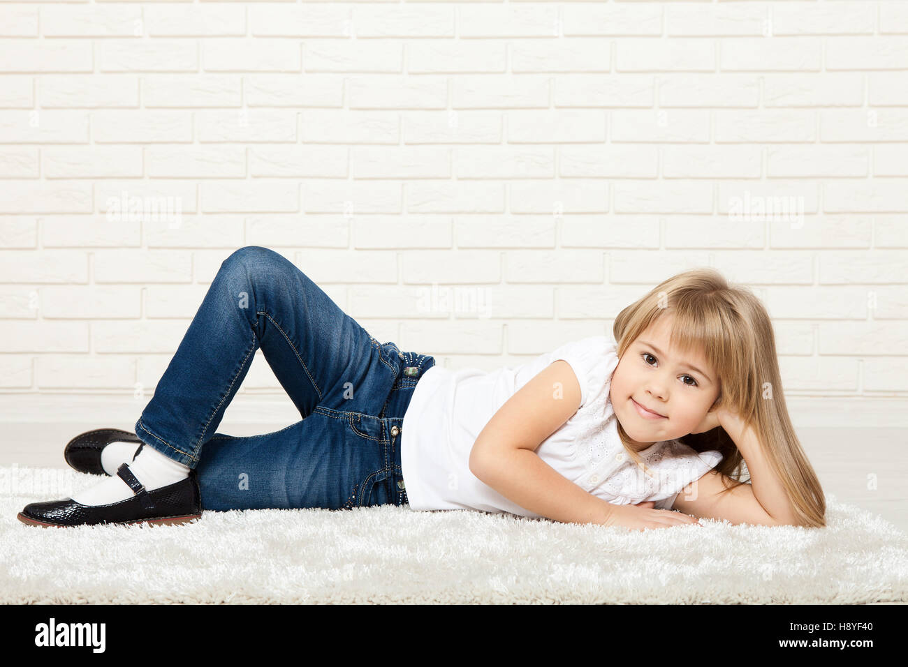 Smiling child girl in cloths lying on floor and relaxing Stock Photo ...