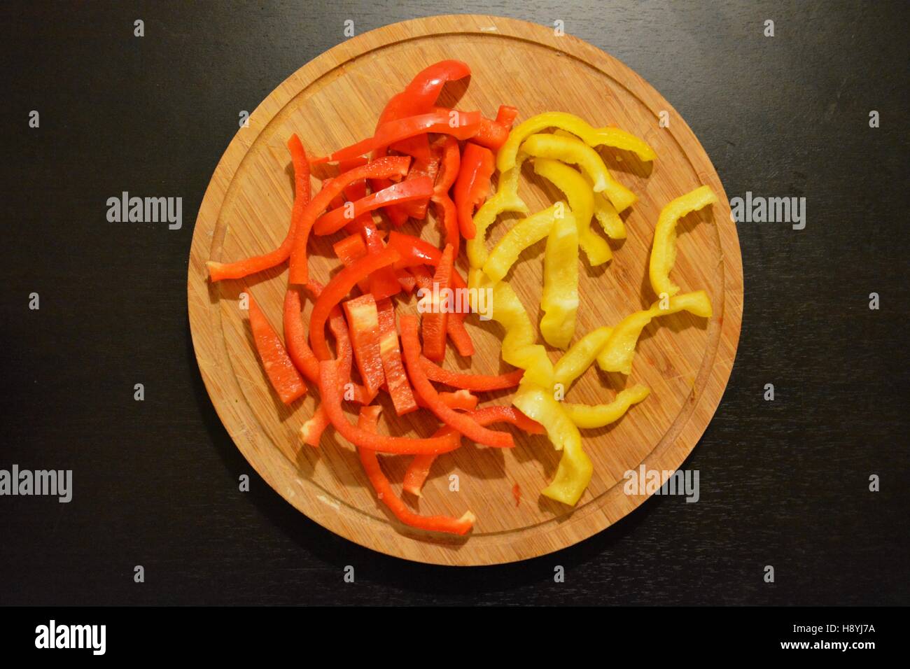 Cut Paprika on a wooden plate from above Stock Photo