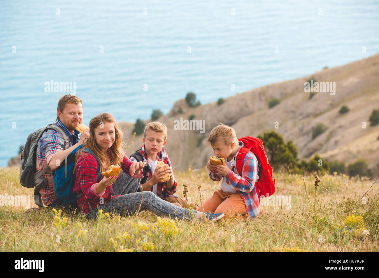 Family of four people eating fastfood in mountains Stock Photo - Alamy