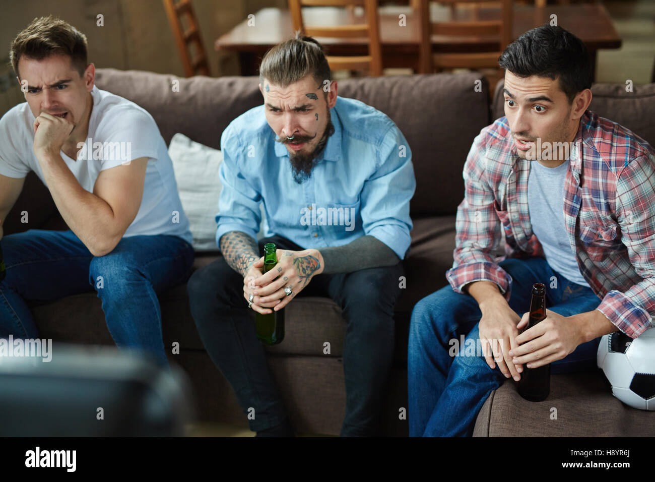 Nervous guys watching tv broadcast of football match Stock Photo