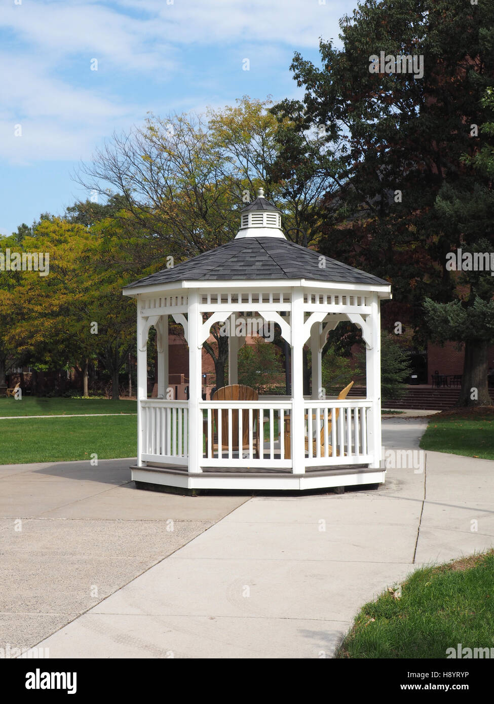 white gazebo by a cement sidewalk and trees Stock Photo