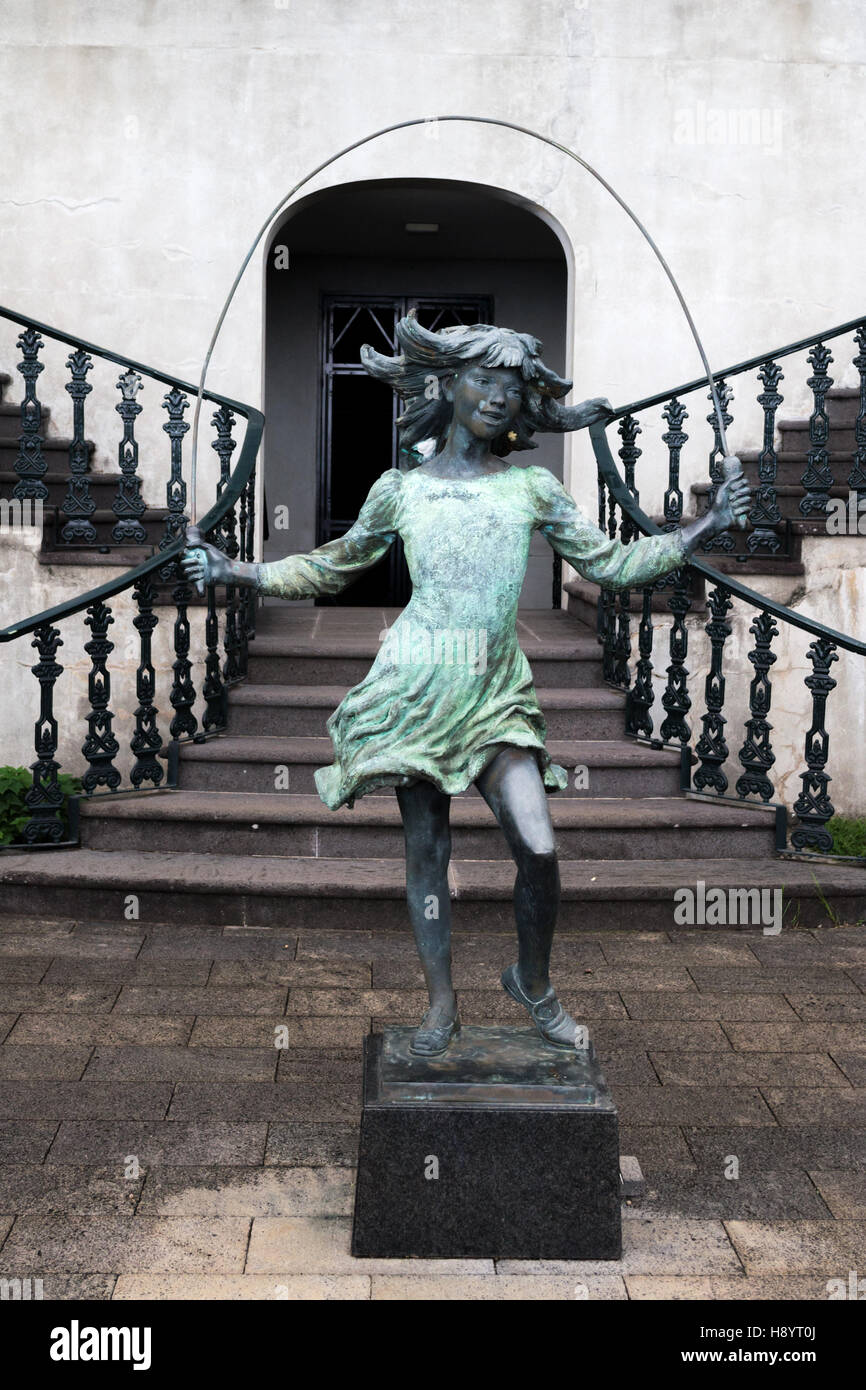 A sculpture of a girl jumping on a rope, monument of a jumping girl if front of a building Stock Photo