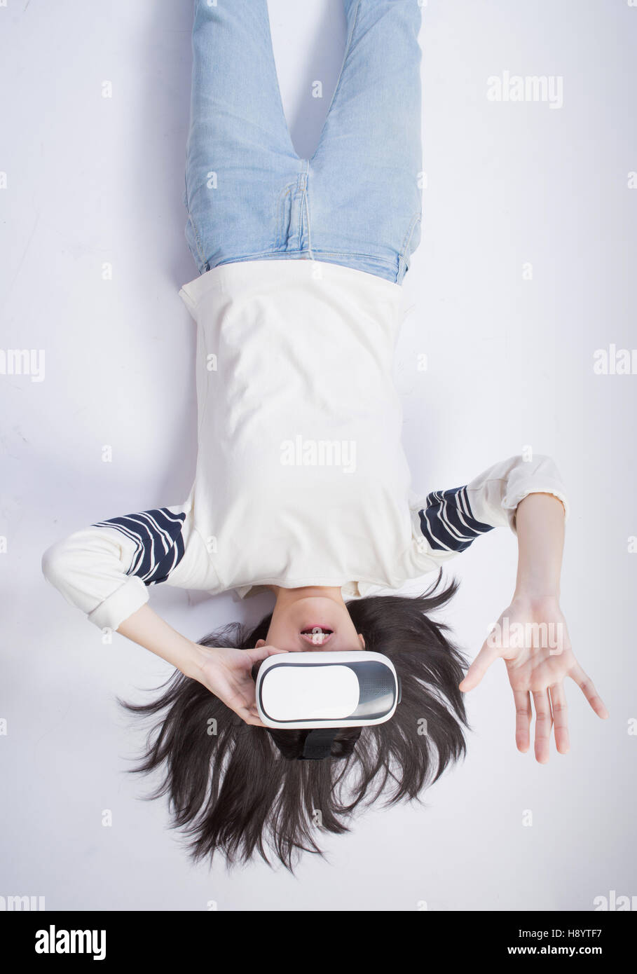 asian woman wearing VR headset, lying upside down, isolated white