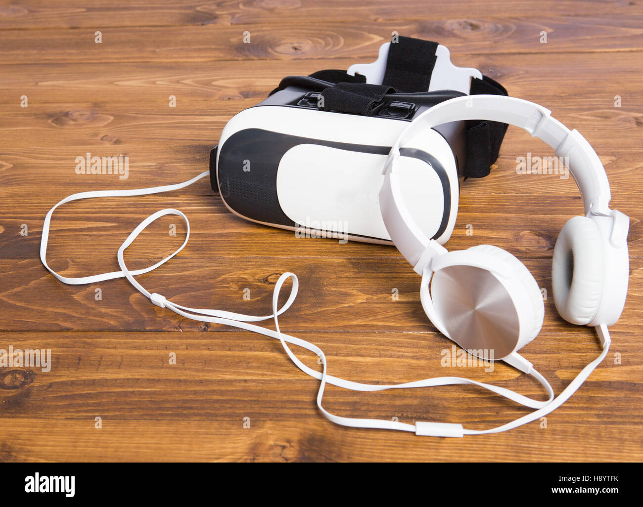 VR headset and circumaural earphone put together in a mess, isolated on wooden floor background Stock Photo