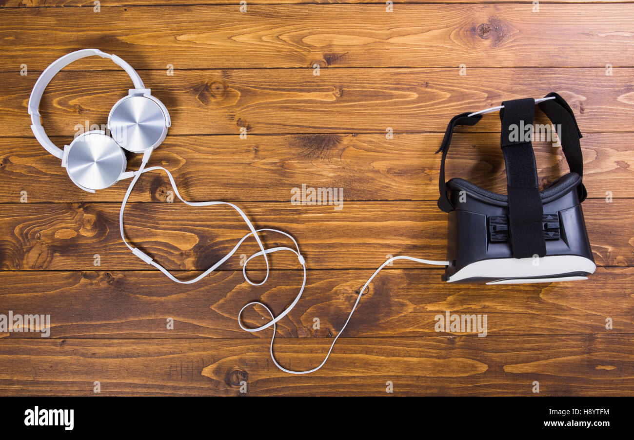 separated VR headset and earphones, isolated on wooden floor background Stock Photo