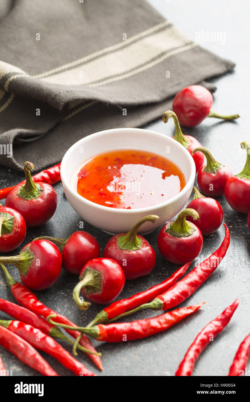 Red chili peppers and chili sauce on kitchen table Stock Photo Alamy
