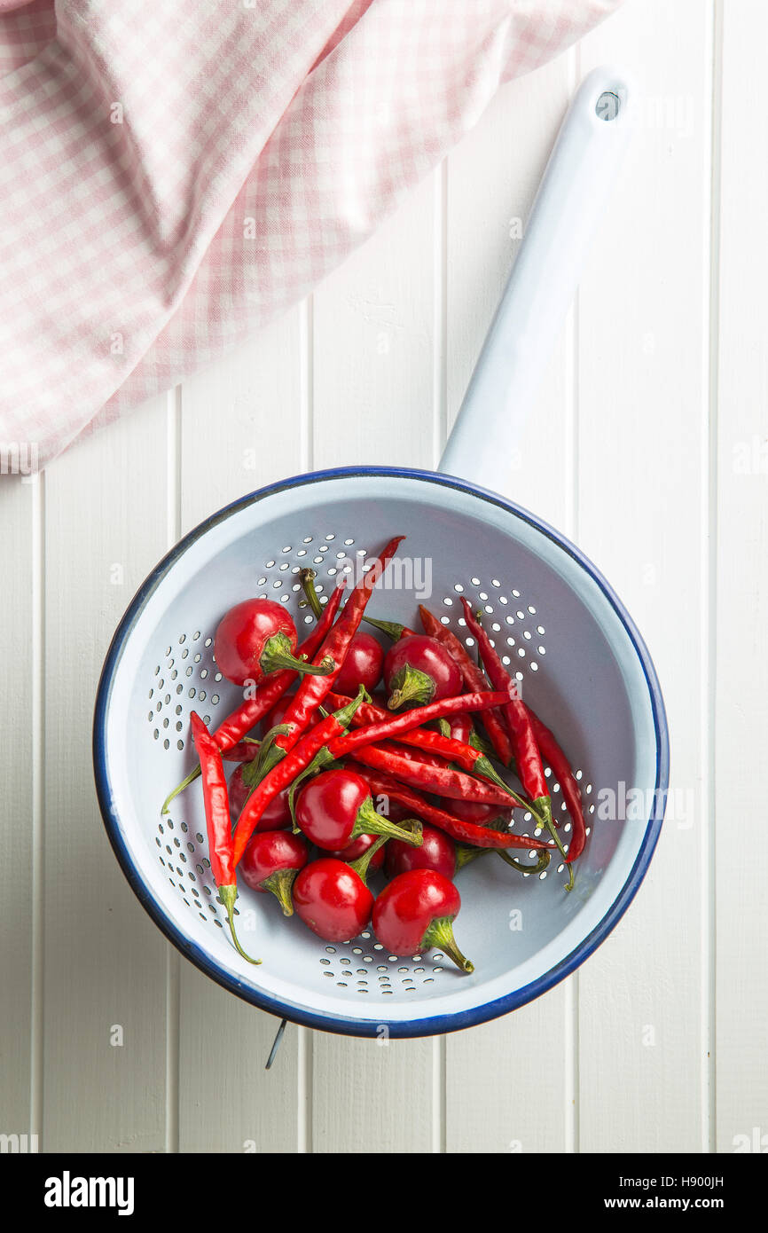 Red chili peppers in colander. Top view Stock Photo - Alamy