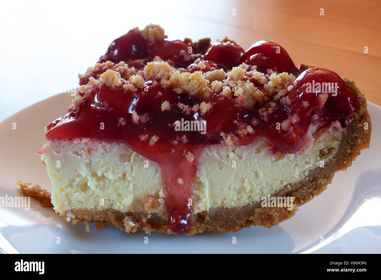 Cheescake with graham cracker crust and cherry topping that is running