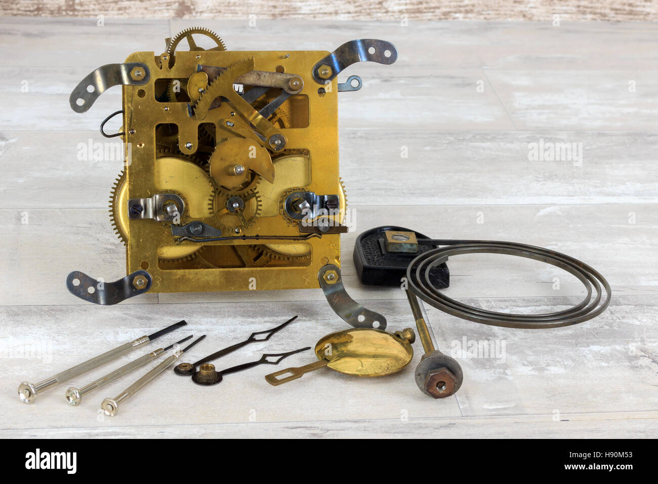 Old brass clock mechanism with pendulum, chime spring and three small screwdrivers Stock Photo