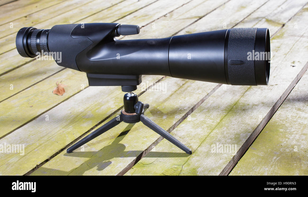 Black spotting scope with a tripod on a wood deck Stock Photo