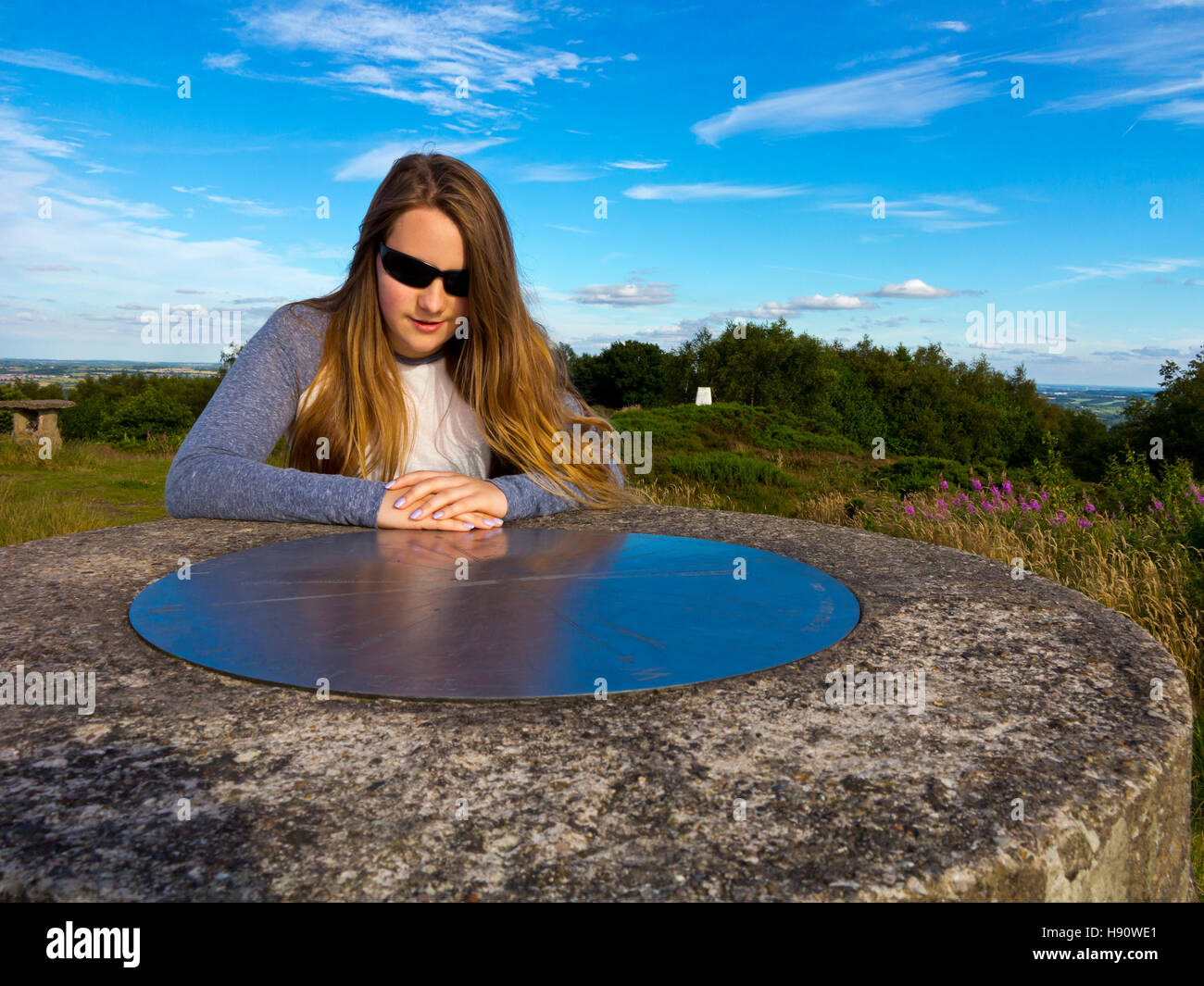 Teenage girl with long hair enjoying a country walk in summer looking at a viewpoint information disc Stock Photo