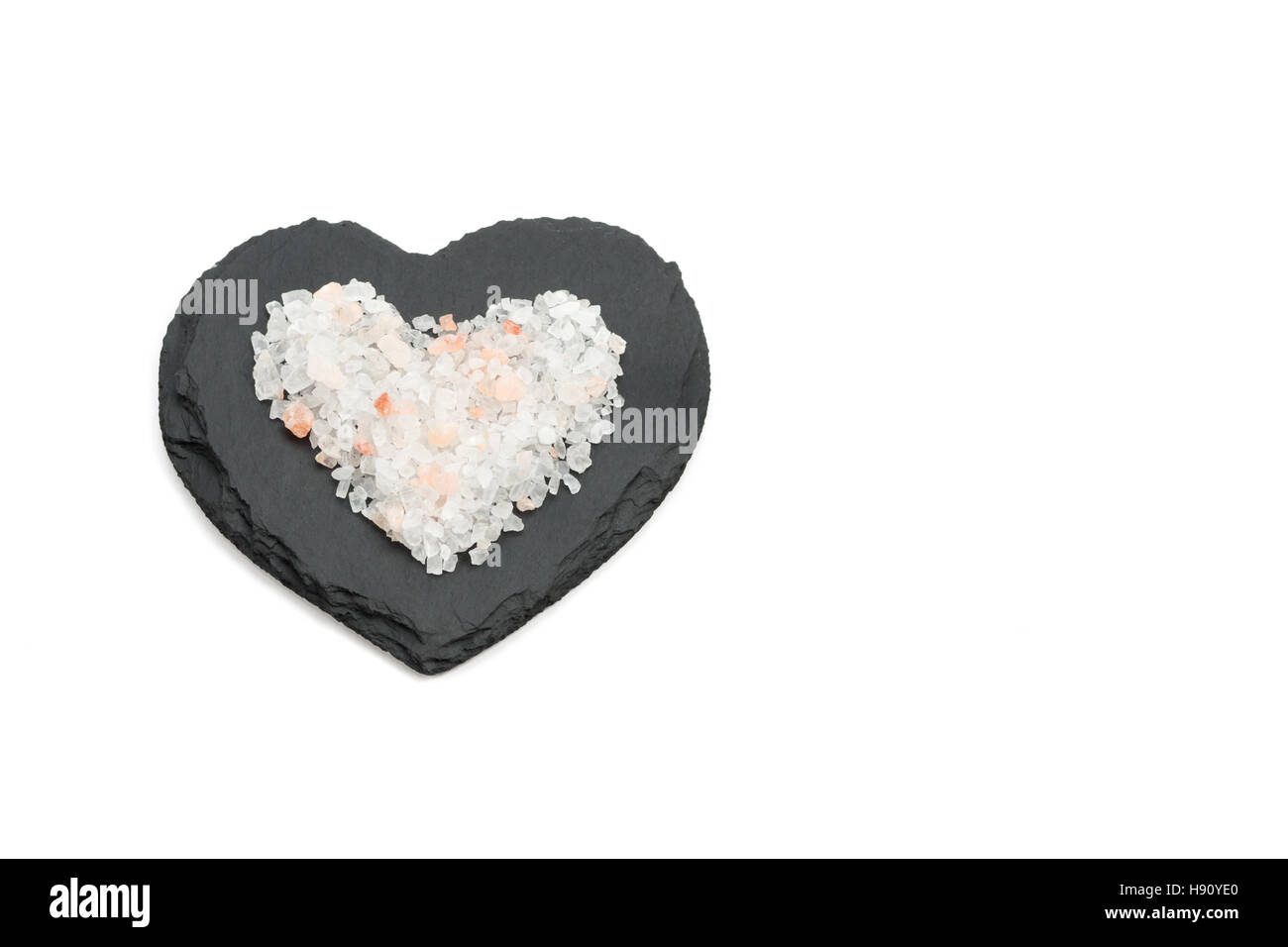 Pink salt crystals on black heart shaped slate Stock Photo