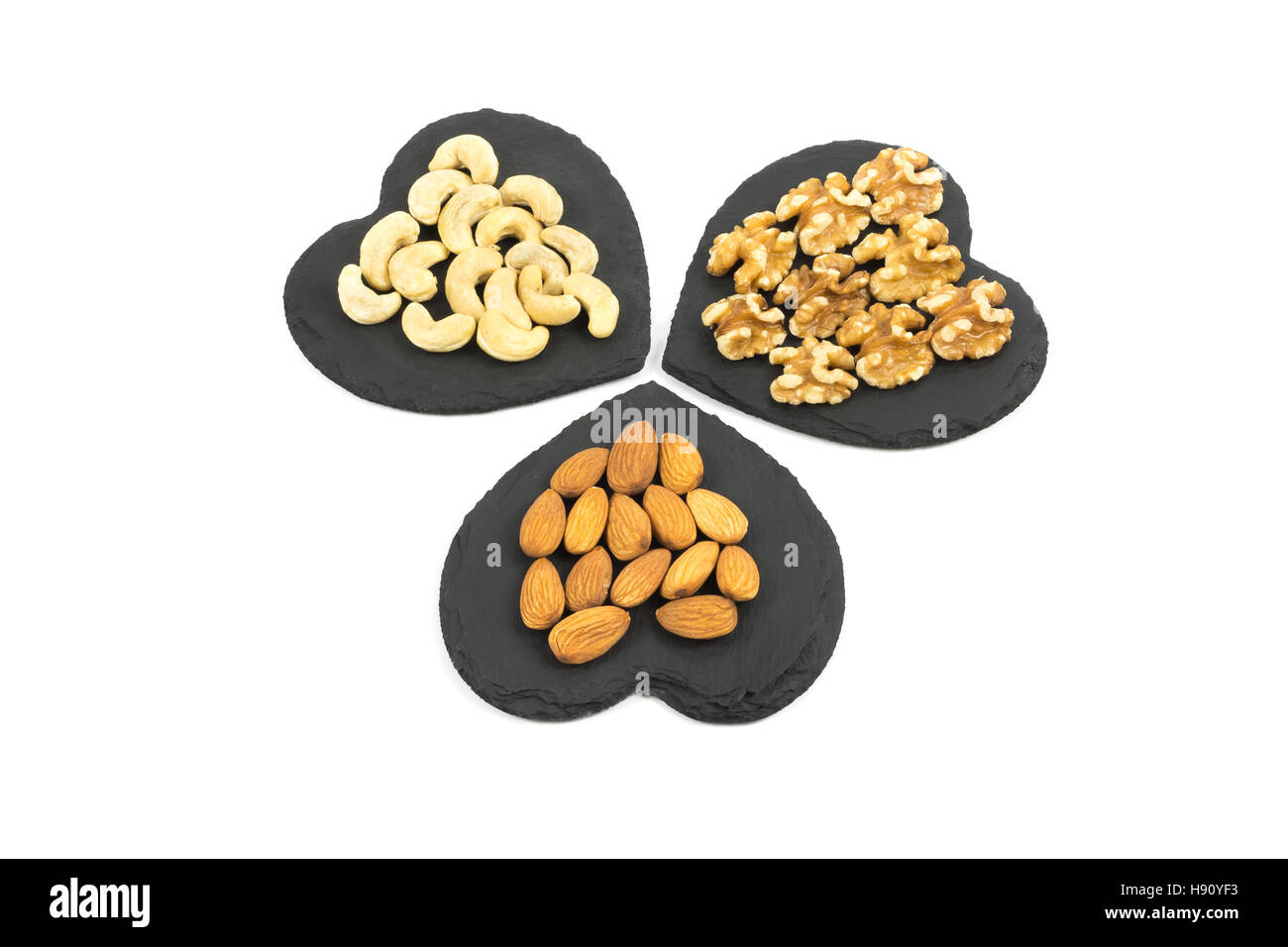 A trio of Almonds, Cashews and walnuts on heart shaped slates isolated
