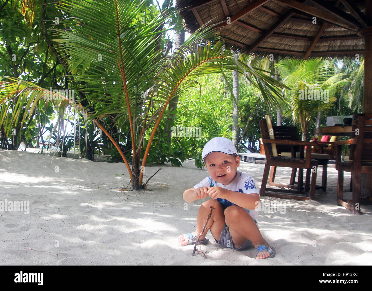 3 year old kid on a beach near a bar in maldives Stock Photo