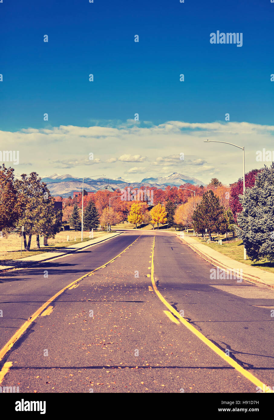 Retro stylized photo of an autumn road with Rocky Mountains in distance, Colorado, USA. Stock Photo