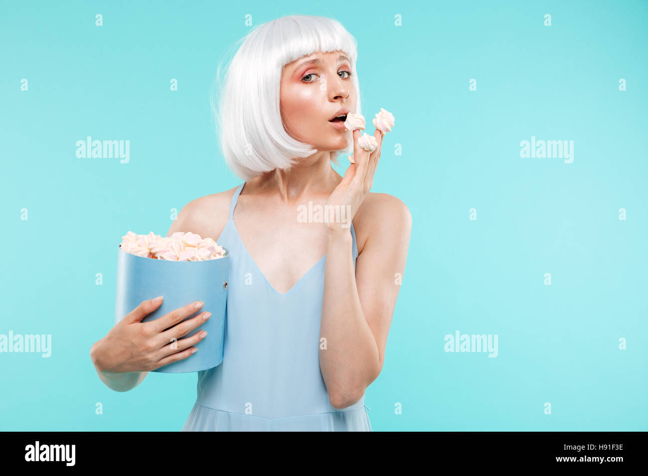 Lovely blonde young woman eating marshmallows from the box Stock Photo