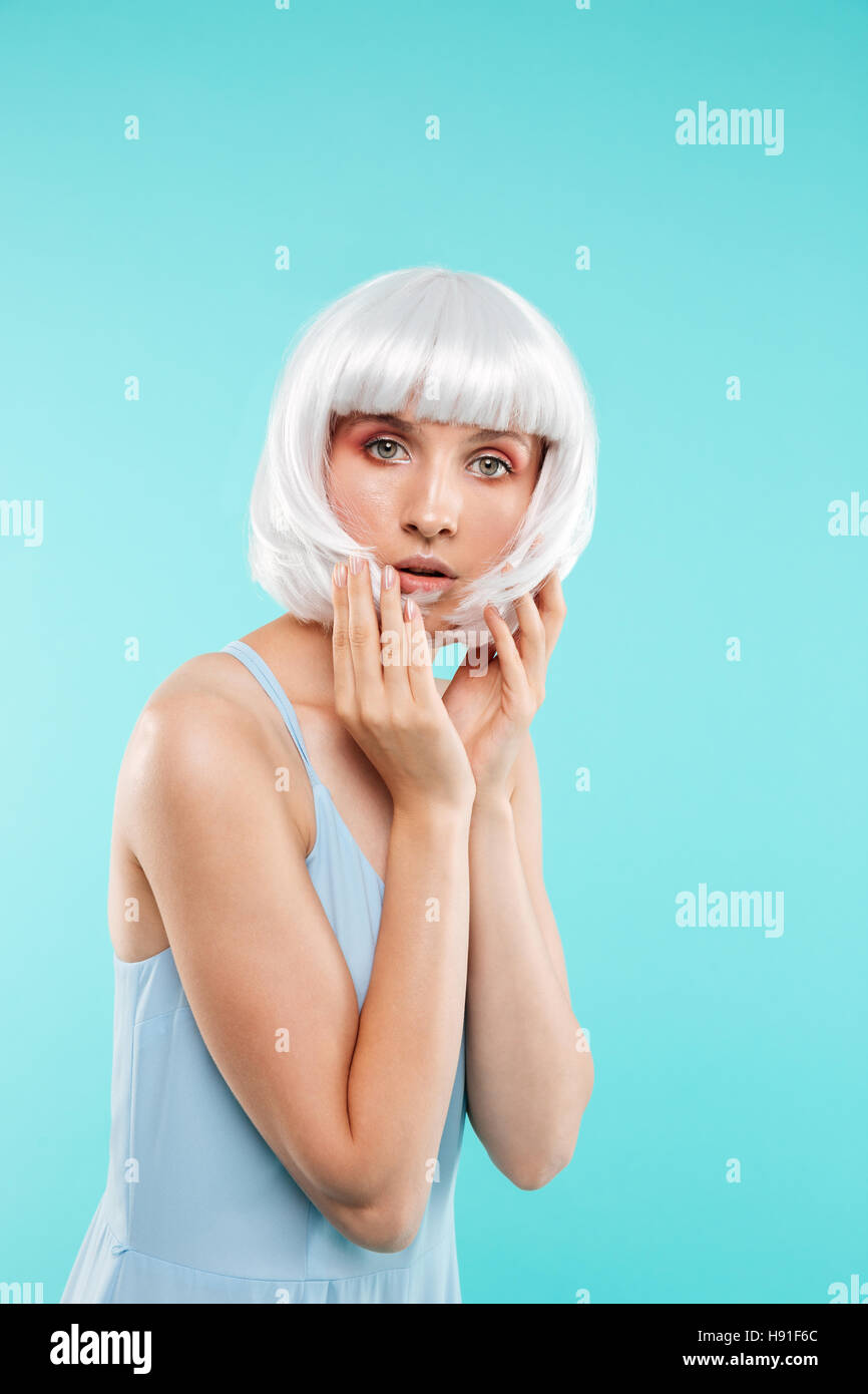 Portrait of attractive young woman in blonde wig over blue background