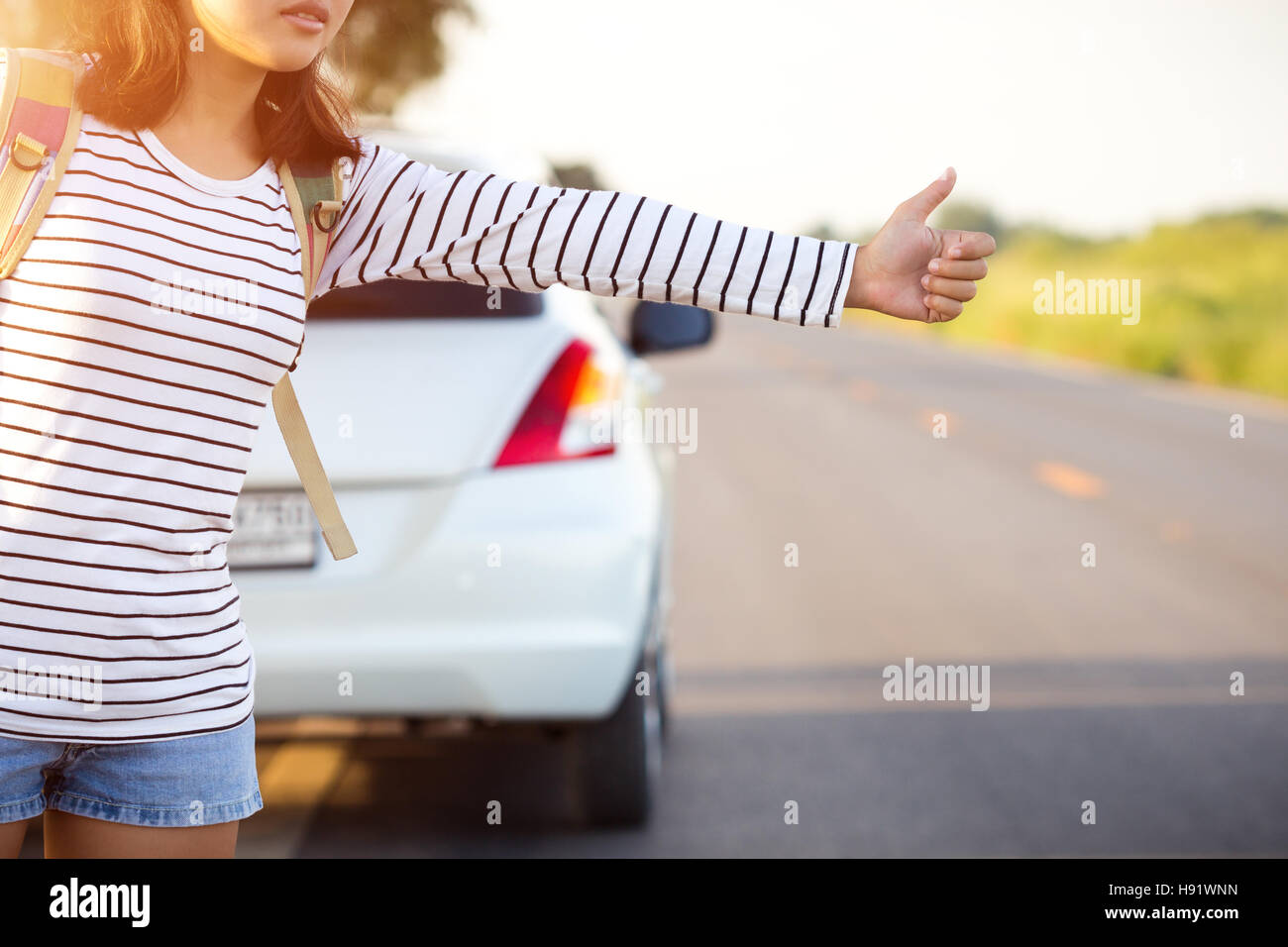 woman hitchhiking looking for help with her broken car on the road Stock Photo
