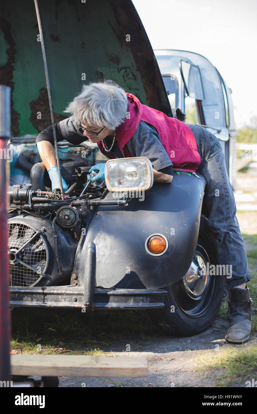Elderly car mechanic working on her vintage car Stock Photo