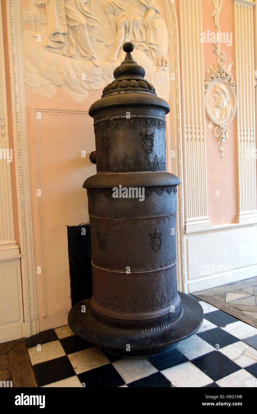 Old wood stove in cast iron and column in front of a pink wall Stock Photo