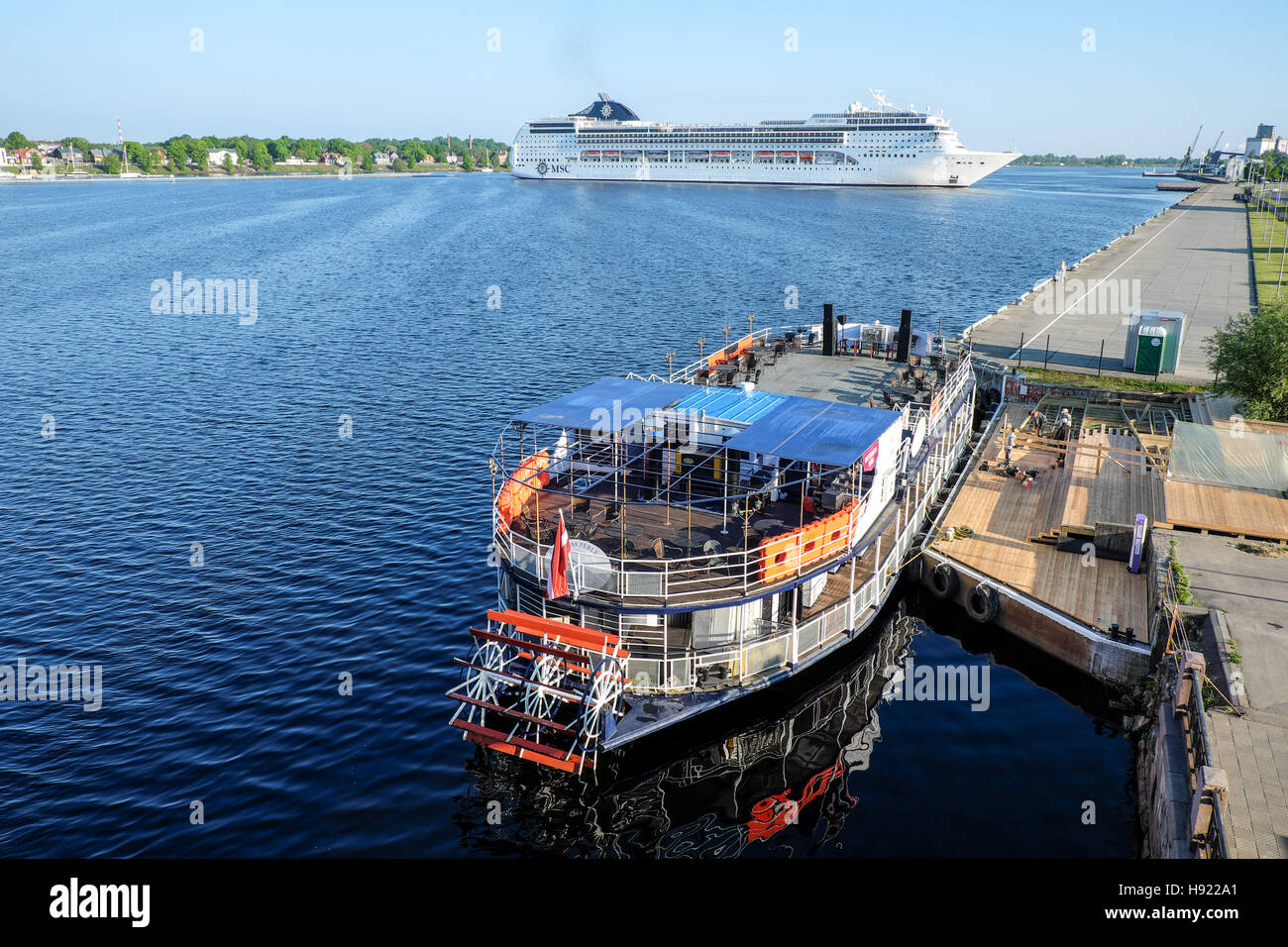 Riga, Latvia - May 21, 2016: Cruise Ship MSC Opera turning round and Touristic river boat with paddle wheel by the city embankment Stock Photo