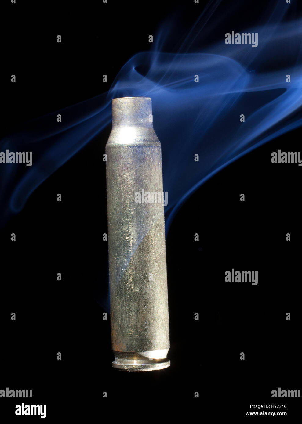 Brass casing from ammunition that has been fired and is smoking Stock
